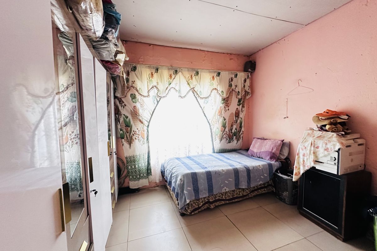 A bedroom featuring tiled flooring and a built-in wardrobe, currently requiring cosmetic updates to the wall and ceiling finishes.