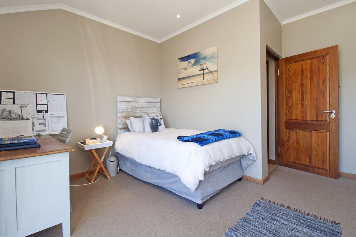 A well-maintained bedroom featuring neutral wall tones, carpeted flooring, and a solid timber door.