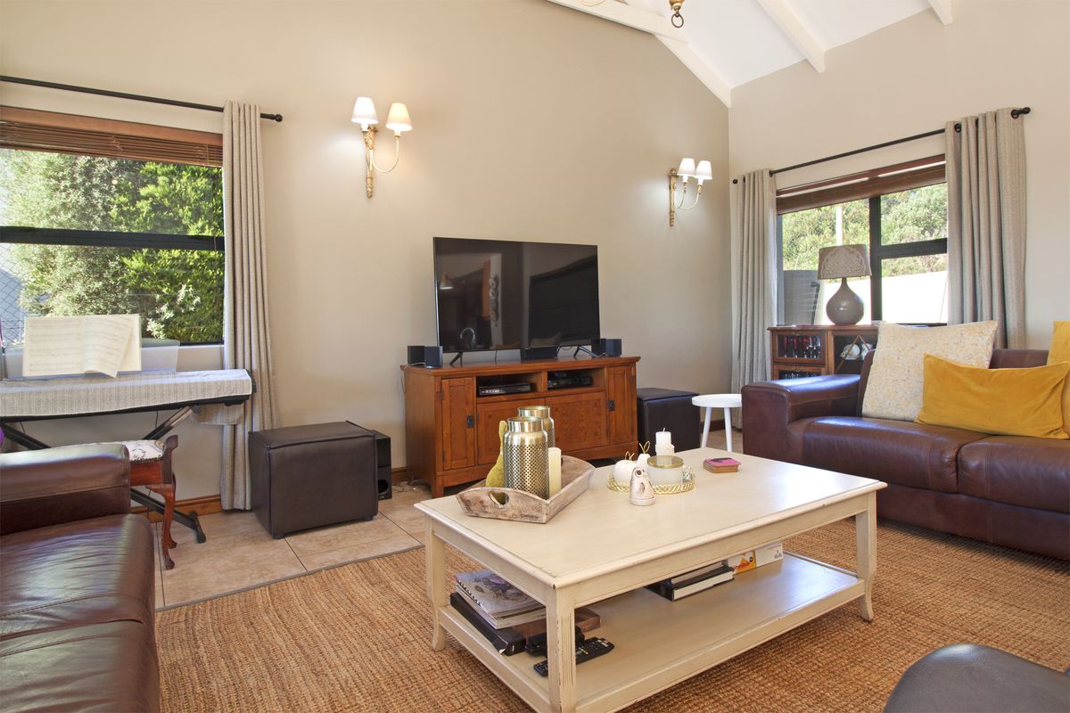 A spacious living room featuring high vaulted ceilings with exposed beams, large windows, and tiled flooring, creating a bright and comfortable atmosphere.