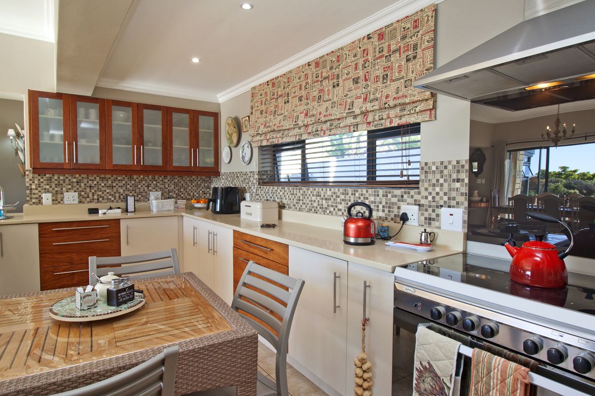 A well-maintained kitchen featuring wooden cabinetry, stone countertops, a mosaic tile backsplash, and a built-in stainless steel oven with an extractor fan.
