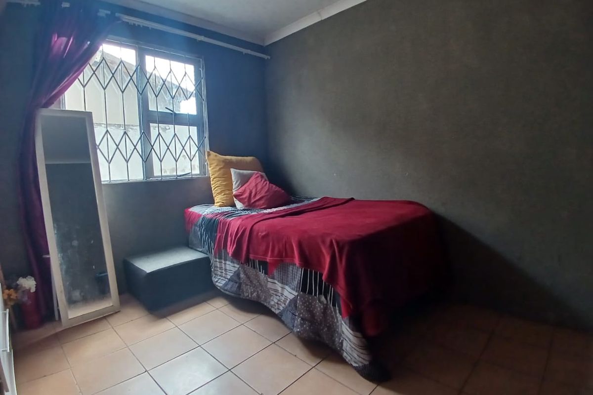 A bedroom featuring tiled flooring, a window with a security gate, and coving detail.