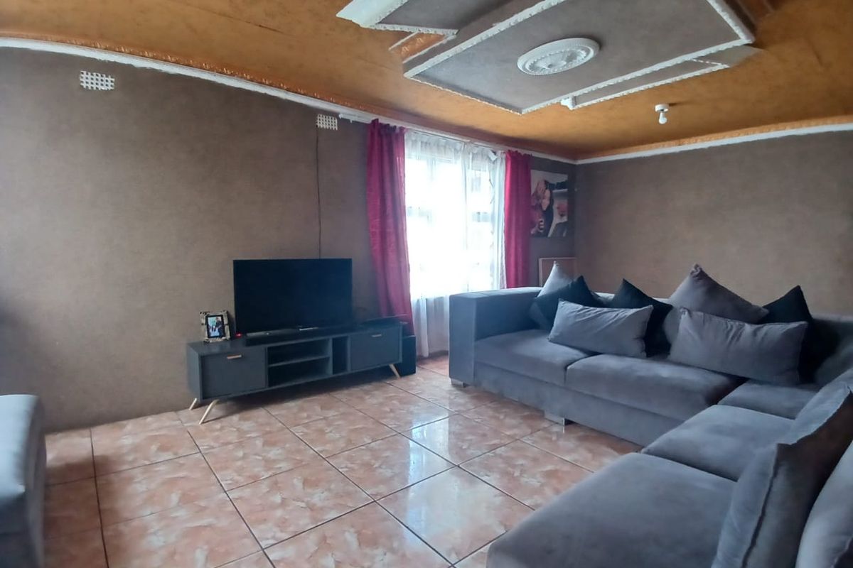 A living room featuring tiled flooring and a decorative ceiling with recessed molding.