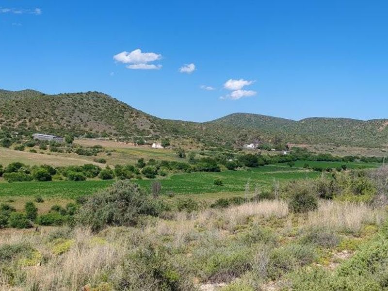 Expansive rural landscape view featuring rolling hills, cultivated green fields, and natural vegetation typical of a farm setting.