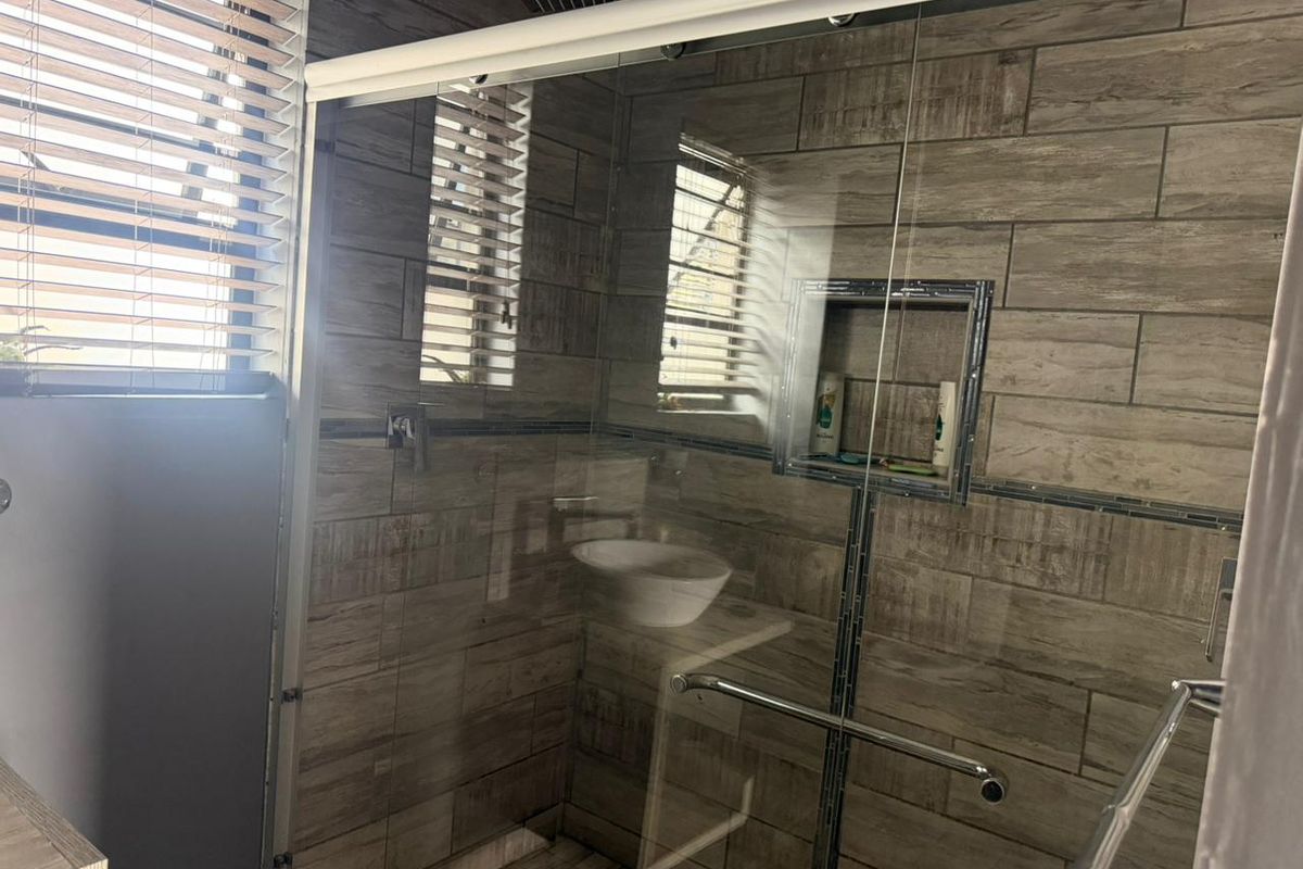Modern bathroom featuring a spacious walk-in shower with wood-look tiling, a built-in recessed niche, and a contemporary rain shower head.