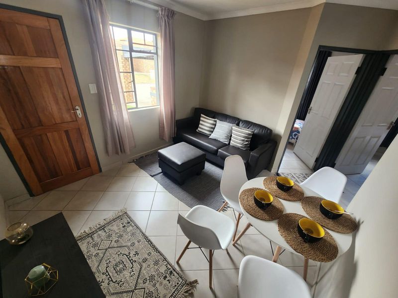 Open plan living and dining area featuring tiled flooring, neutral wall tones, and direct access to adjacent rooms via timber and panel doors.