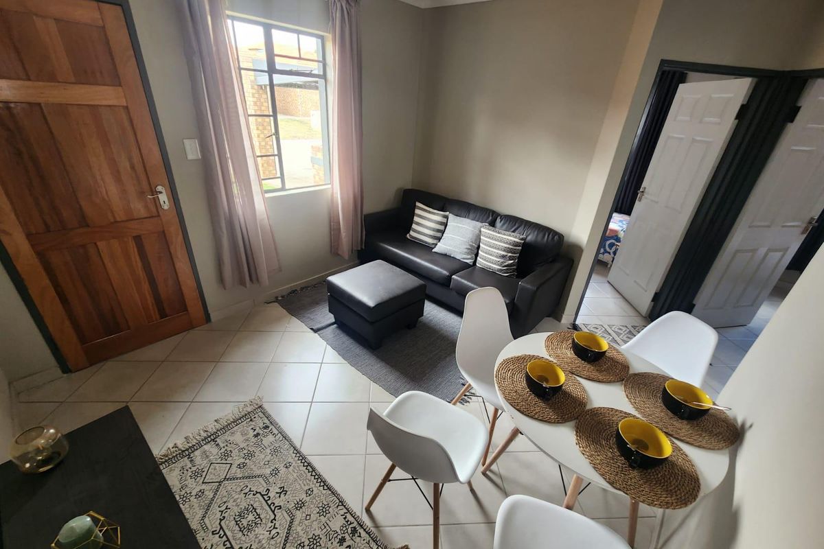 Open plan living and dining area featuring tiled flooring, neutral wall tones, and direct access to adjacent rooms via timber and panel doors.