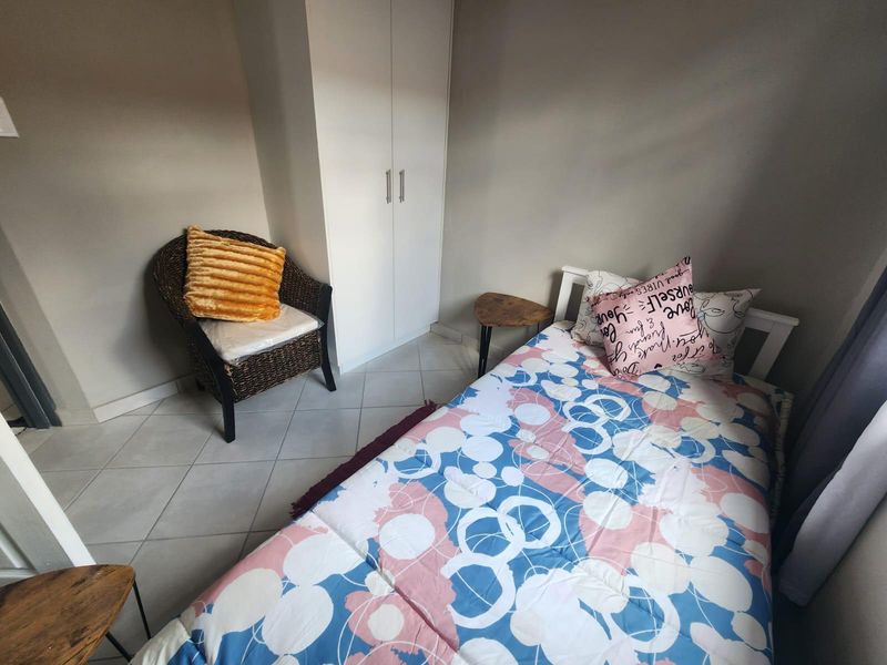 A compact bedroom featuring tiled flooring and a built-in wardrobe, providing functional storage space.