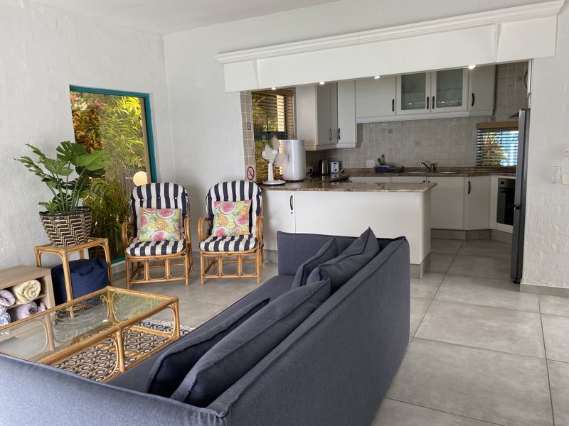 Open plan living area featuring a functional kitchen with granite countertops, built-in cabinetry, and tiled flooring, seamlessly connected to the lounge space.