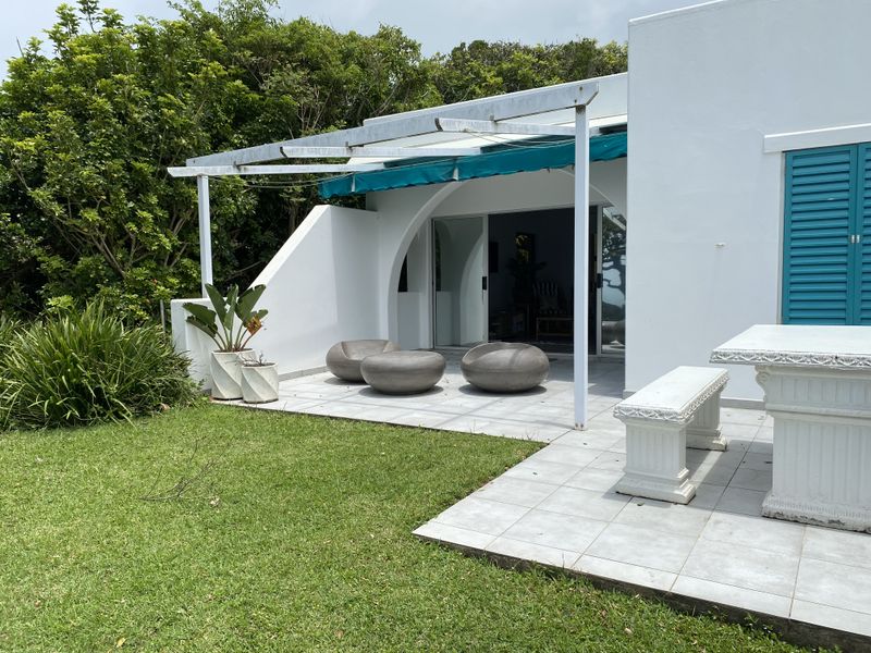A tiled outdoor patio area featuring a retractable awning, sliding glass door access, and direct access to the garden.