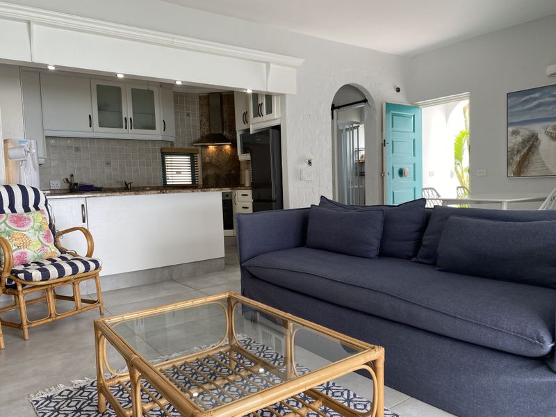 Open-plan living area featuring a functional kitchen with granite countertops, tiled flooring, and an arched doorway leading to an outdoor space.