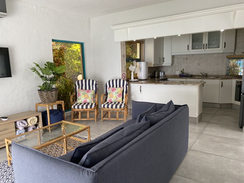 Open-plan living area featuring a functional kitchen with granite countertops, tiled flooring, and direct access to a bright, naturally lit living space.