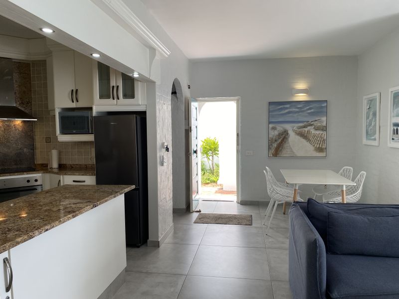 Open-plan living and kitchen area featuring granite countertops, built-in cabinetry, and direct access to an outdoor space through a main entrance.