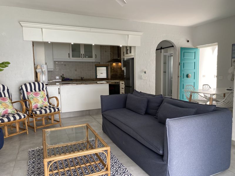 Open-plan living area featuring a functional kitchen with granite countertops, tiled backsplash, and built-in appliances, flowing into a comfortable lounge space.