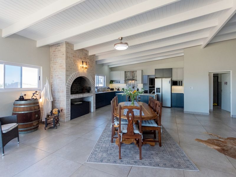 Spacious open-plan living and dining area featuring a prominent brick fireplace, exposed beam ceilings, and a modern kitchen with integrated cabinetry and island.