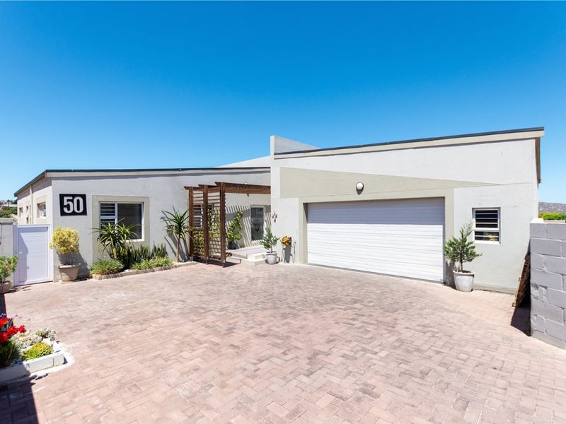 Front elevation of the property featuring a paved driveway, double garage, and a timber pergola entrance.