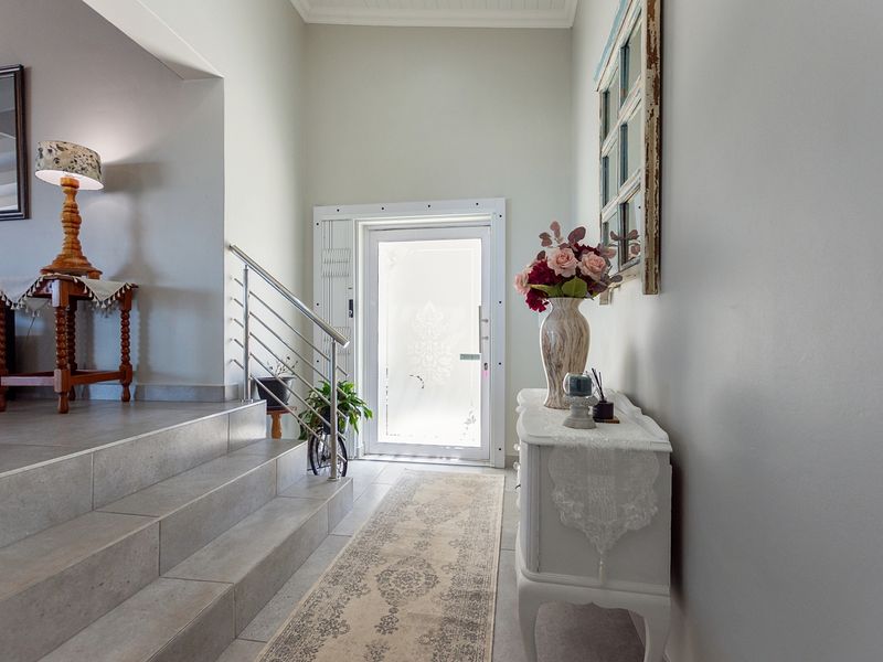 Welcoming entrance hall featuring a tiled staircase with a modern stainless steel balustrade and a decorative frosted glass front door.