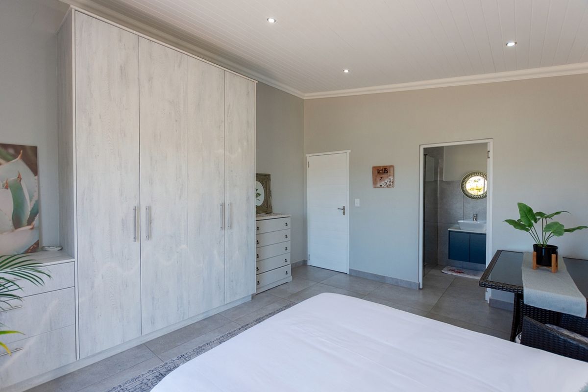 Spacious bedroom featuring built-in cupboards, tiled flooring, recessed lighting, and direct access to an en-suite bathroom.