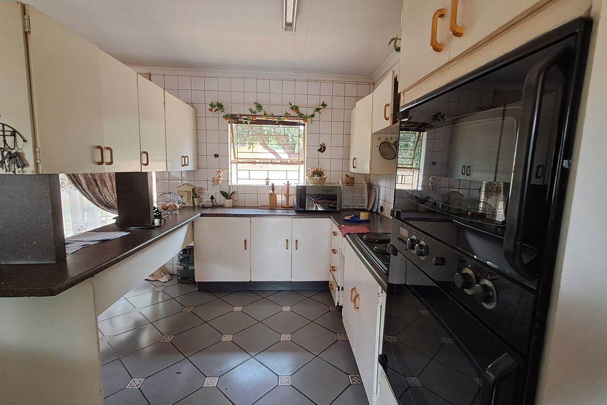 A functional kitchen featuring built-in cabinetry, laminate countertops, a tiled backsplash, and integrated oven and hob, offering a classic layout with potential for modernization.