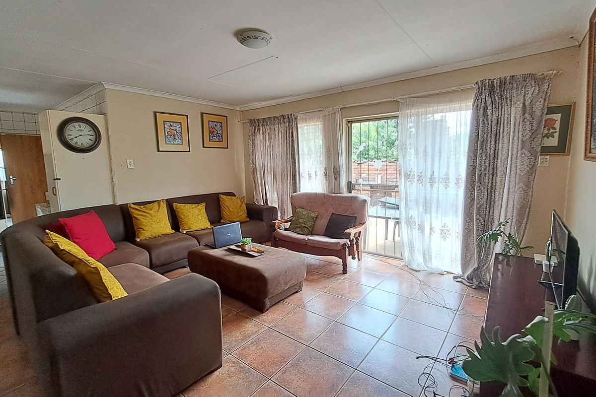 A spacious living room featuring tiled flooring and a sliding glass door that provides access to the outdoor area.