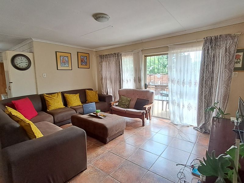 A spacious living room featuring tiled flooring and a sliding glass door that provides access to the outdoor area.
