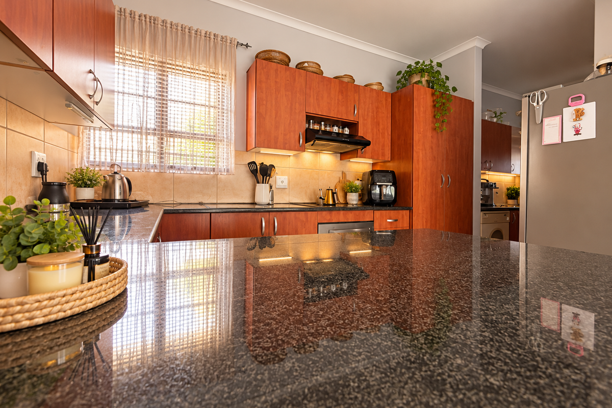 A well-maintained kitchen featuring dark granite countertops, warm-toned laminate cabinetry, and a tiled backsplash, offering a functional and classic cooking space.
