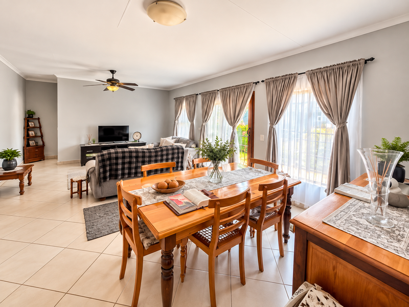 Spacious open-plan living and dining area featuring neutral walls, tiled flooring, and large sliding glass doors that provide ample natural light.
