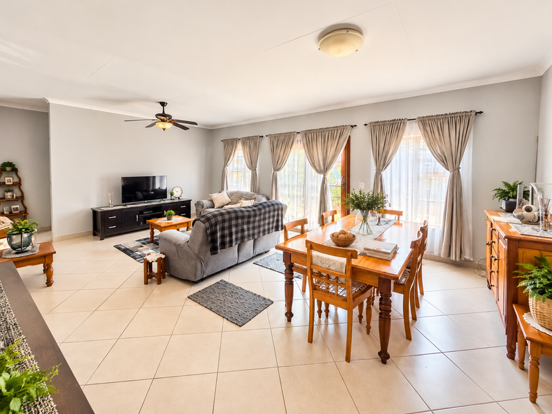 Spacious open-plan living and dining area featuring neutral tiled flooring, a ceiling fan, and large sliding glass doors that provide ample natural light.