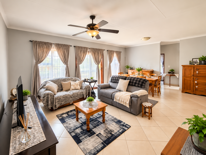 Spacious open-plan living and dining area featuring neutral tiled flooring, a ceiling fan, and large sliding glass doors providing ample natural light.