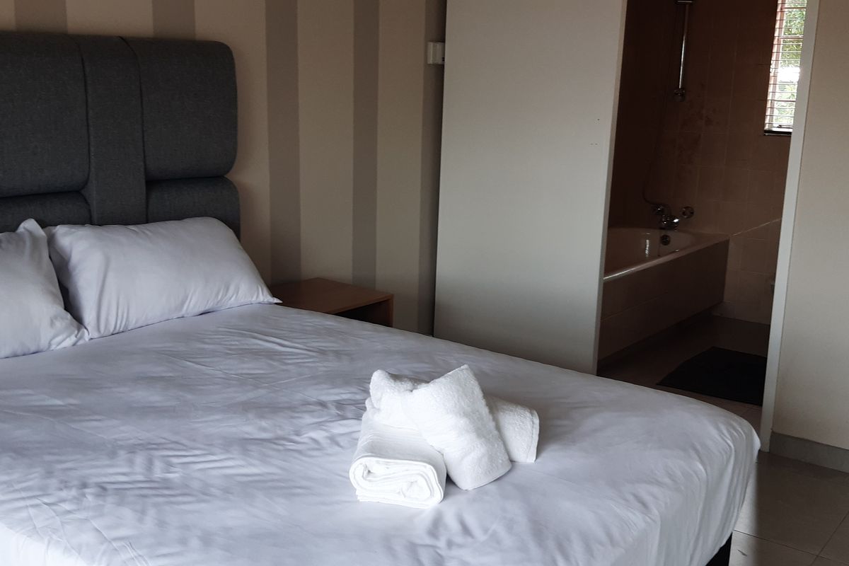 A bedroom featuring an open-plan layout with an en-suite bathroom area containing a built-in bathtub and tiled flooring.