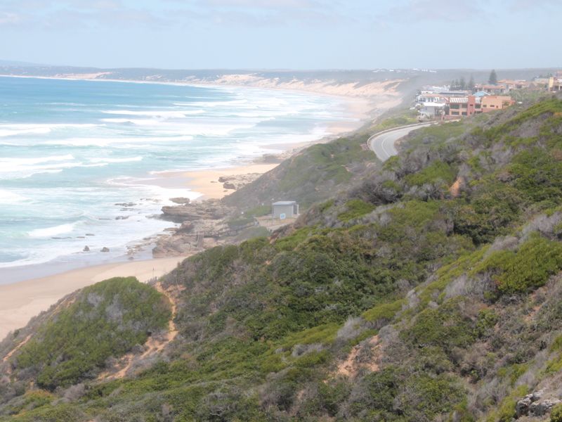 A scenic coastal view overlooking the ocean, sandy beach, and surrounding natural landscape, highlighting the property's prime location.