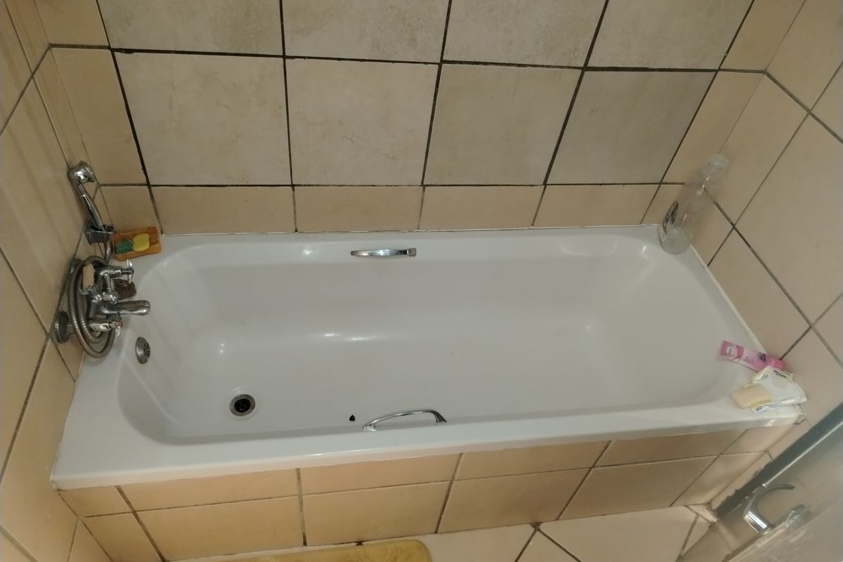 A standard bathroom featuring a built-in bathtub with chrome fixtures and tiled surround.