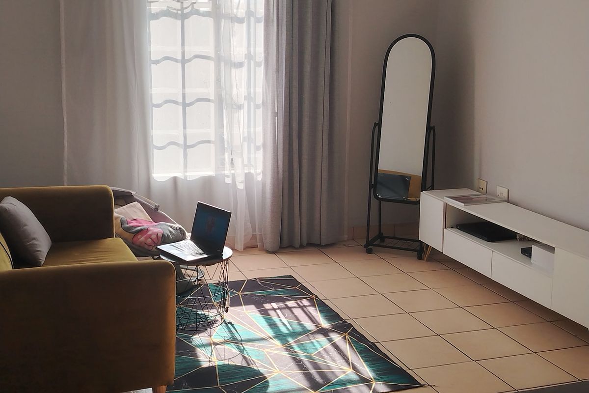 A bright living room featuring tiled flooring and a large window with natural light, providing a functional and comfortable living space.