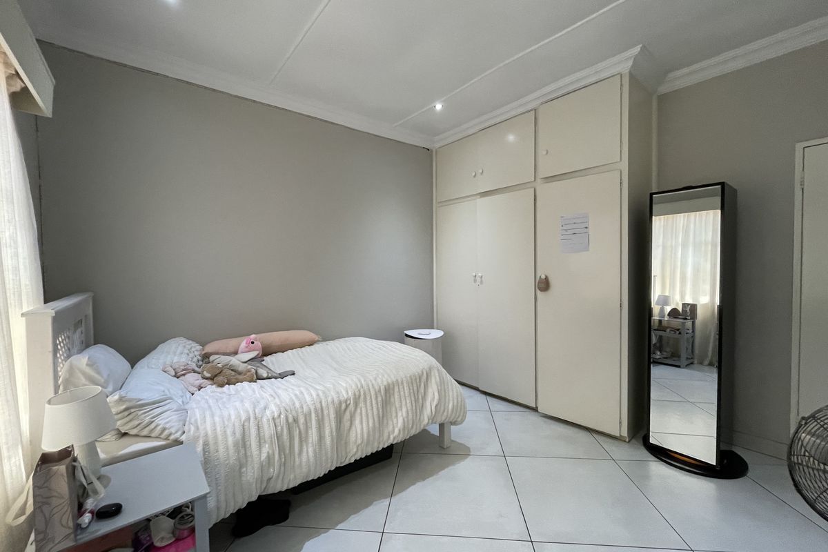 A bedroom featuring tiled flooring, recessed downlighting, and built-in cupboards with overhead storage.