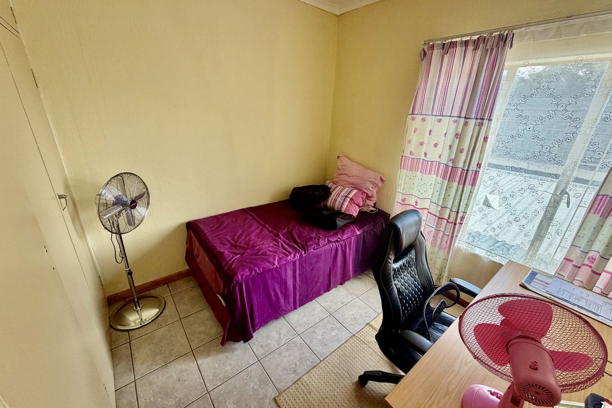 A compact bedroom featuring tiled flooring and a built-in cupboard, offering a functional space that could benefit from modern updates and fresh finishes.