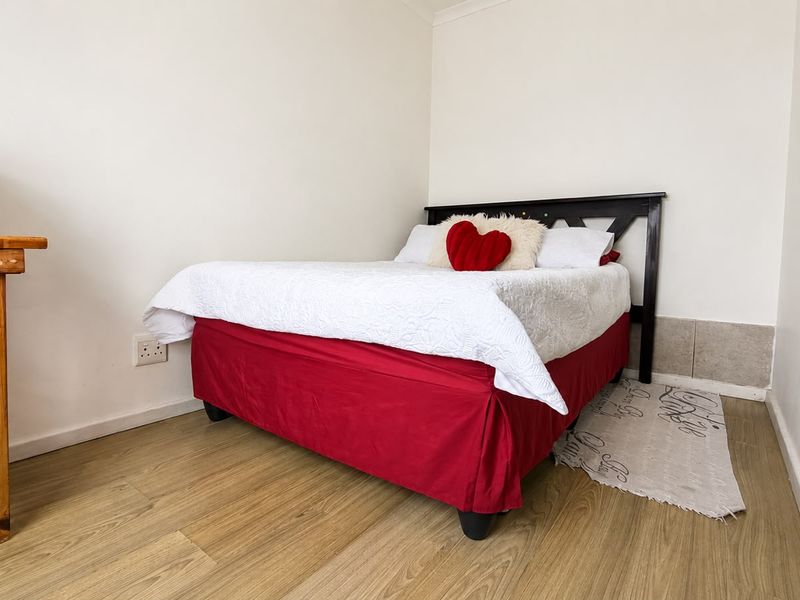 A compact bedroom featuring light-toned laminate flooring and neutral wall finishes, providing a functional space for rest.
