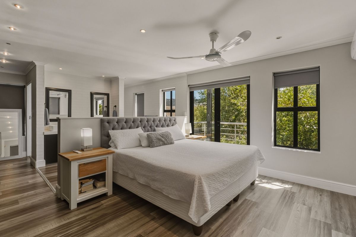 Spacious master bedroom featuring modern laminate flooring, recessed lighting, a ceiling fan, and an open-plan en-suite layout with direct balcony access.