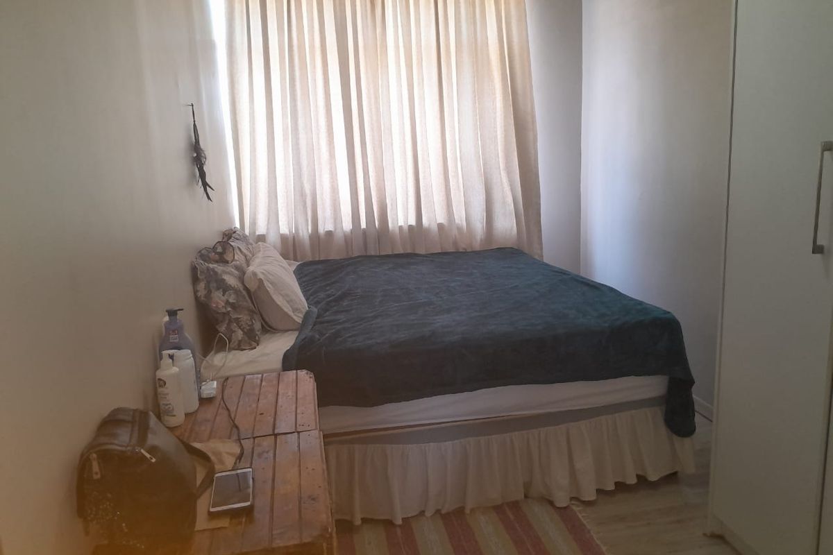 A compact bedroom featuring laminate flooring and a built-in wardrobe, providing functional storage space.
