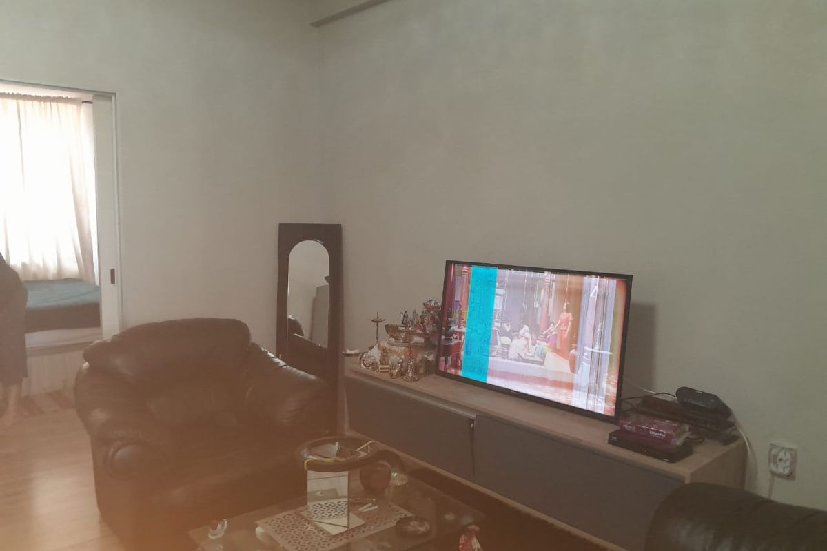 A living room area featuring laminate flooring and a doorway leading to an adjacent bedroom.