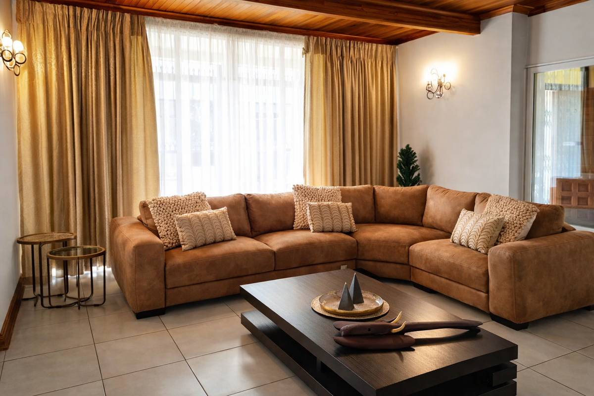 A well-maintained living room featuring a warm timber ceiling, neutral tiled flooring, and elegant wall sconce lighting.
