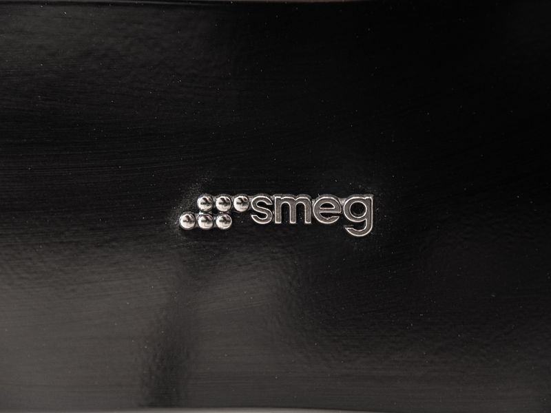 Close-up detail of a Smeg appliance branding on a black finish.