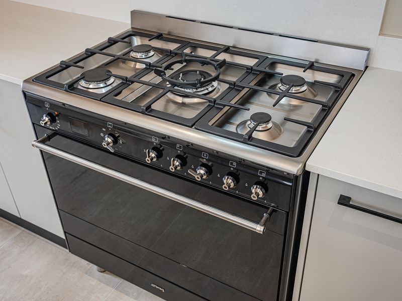 A modern kitchen featuring a high-quality stainless steel gas cooktop and built-in oven set within sleek cabinetry and stone benchtops.