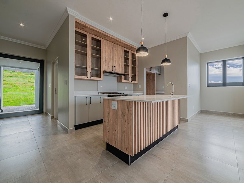 Modern kitchen featuring a slatted wood island, stone countertops, built-in cabinetry, and high-quality finishes, opening onto an outdoor patio area.