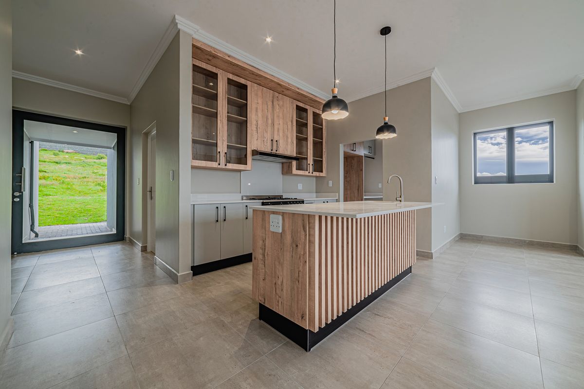 Modern kitchen featuring a slatted wood island, stone countertops, built-in cabinetry, and high-quality finishes, opening onto an outdoor patio area.
