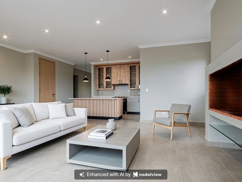 Modern open-plan living area featuring a sleek kitchen with island, tiled floors, and a built-in fireplace, creating a bright and cohesive living space.