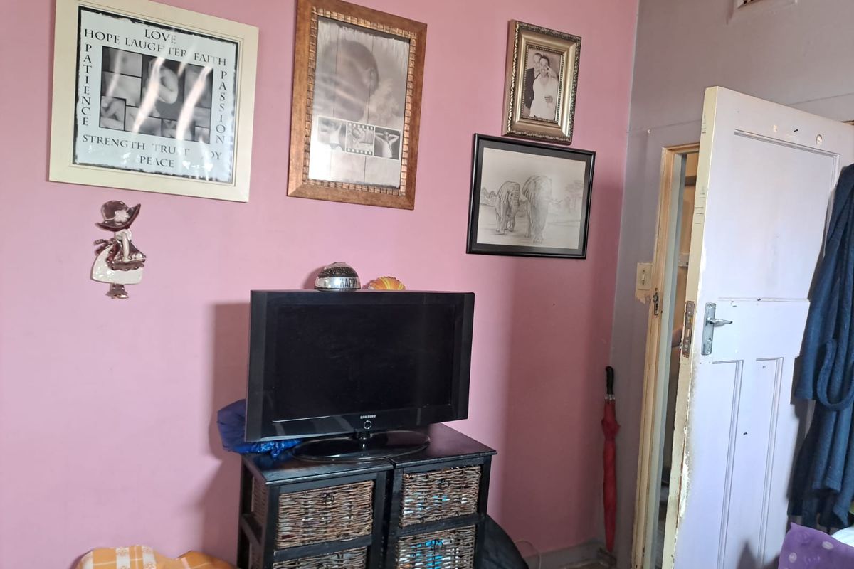 A bedroom featuring pink walls and a standard interior door leading to an adjacent space.
