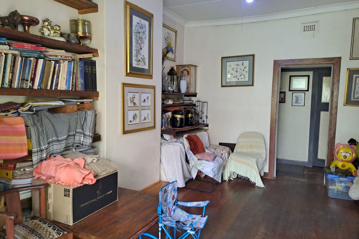 A living room space featuring original timber flooring, built-in wall shelving, and a doorway leading to an adjacent area.