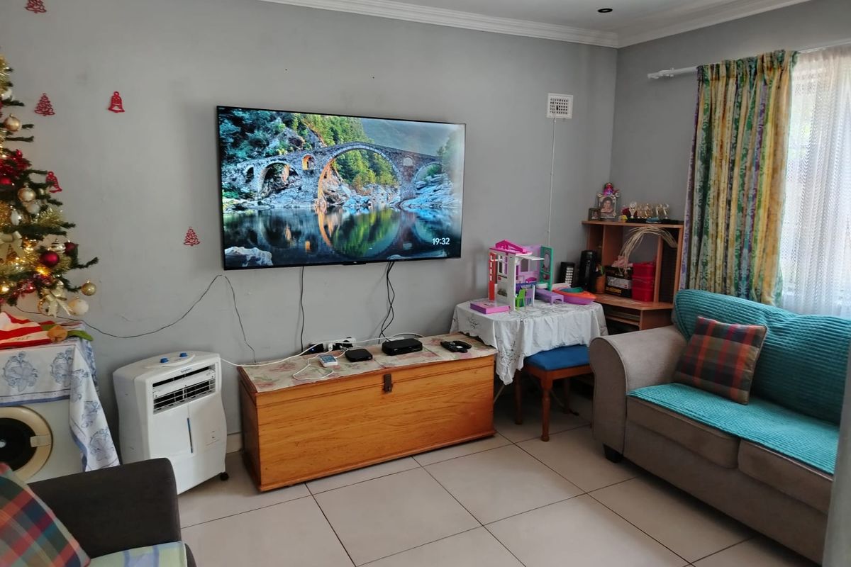 A living room featuring tiled flooring, recessed ceiling lighting, and a wall-mounted television, providing a functional and comfortable living space.