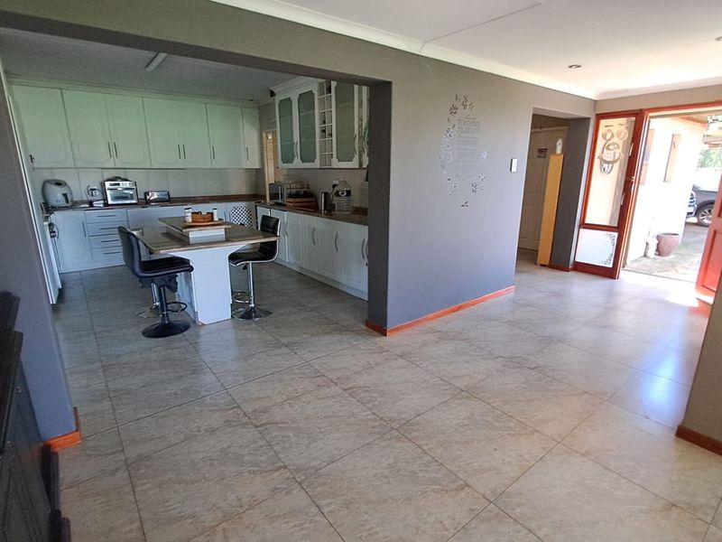 Open plan kitchen and living area featuring tiled flooring, built-in cabinetry, and direct access to an outdoor area through a glass panel door.