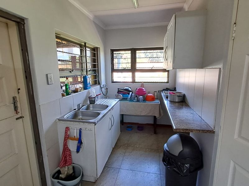 A functional scullery area featuring a double basin sink, laminate countertops, and wall-mounted cabinetry, providing practical utility space for the home.