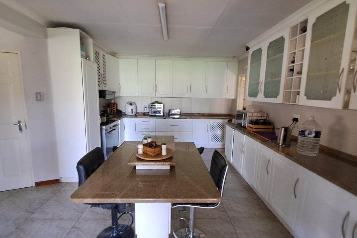 Spacious kitchen featuring white built-in cabinetry, granite countertops, and a central breakfast island, providing ample storage and workspace for meal preparation.